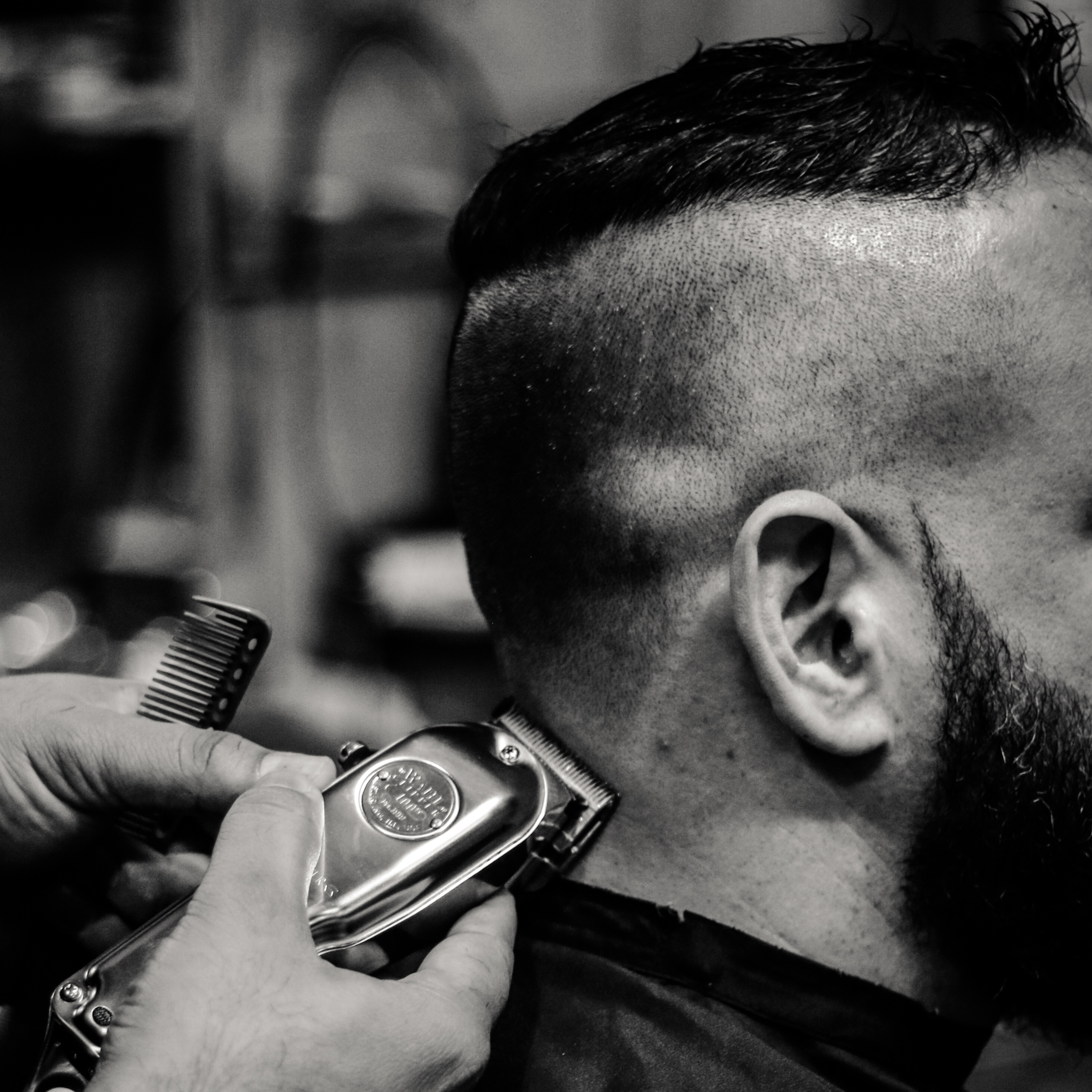 Square close-up image of barber clipping hair